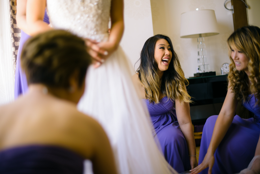 Bridesmaids kneeling on the floor helping a Bride getting ready