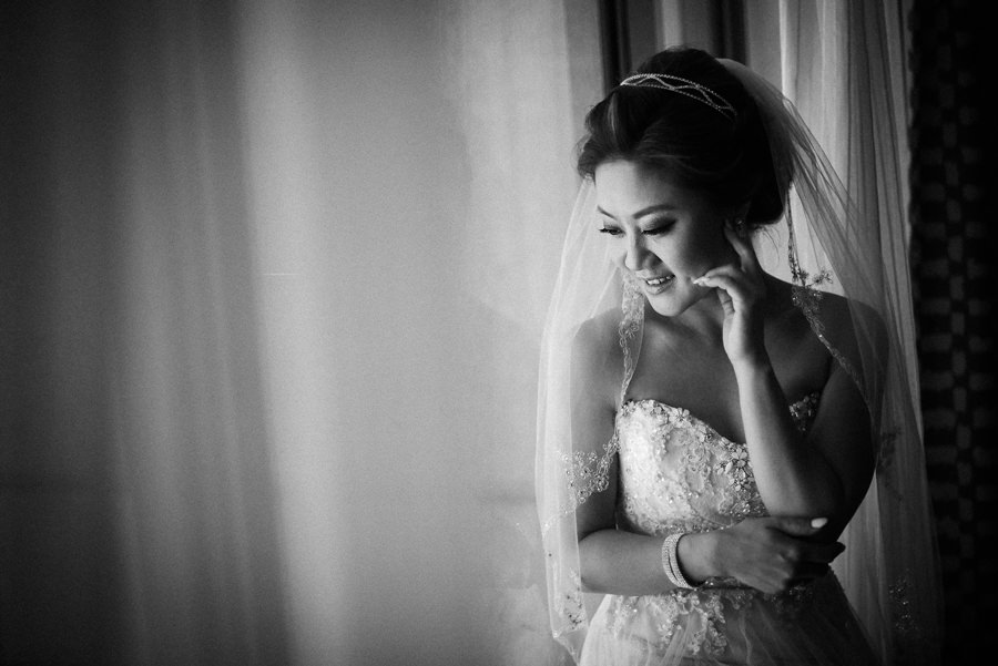 A beautiful bride in her wedding gown standing next to a hotel window