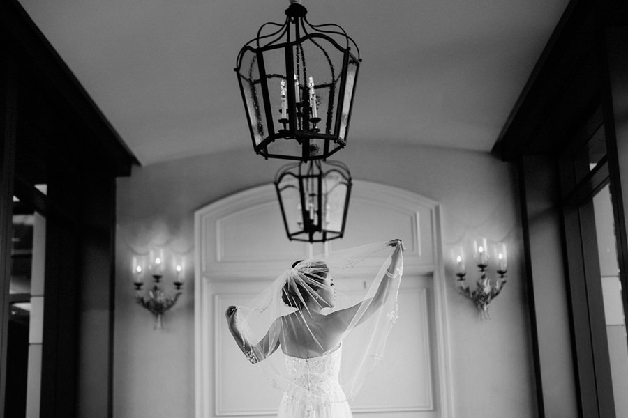 A beautiful bride in a classical pose lifting up her veil