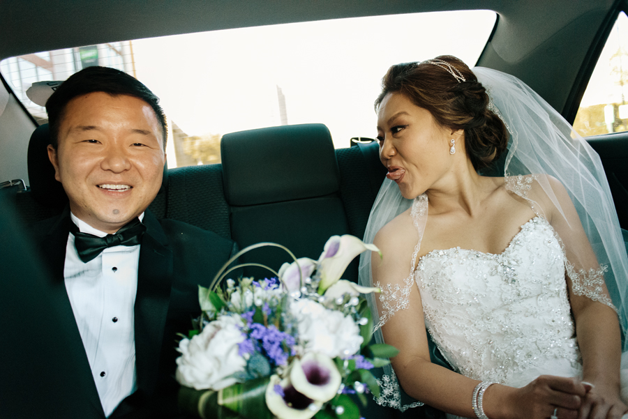 A bride making faces to her groom in the car as they go to the ceremony place